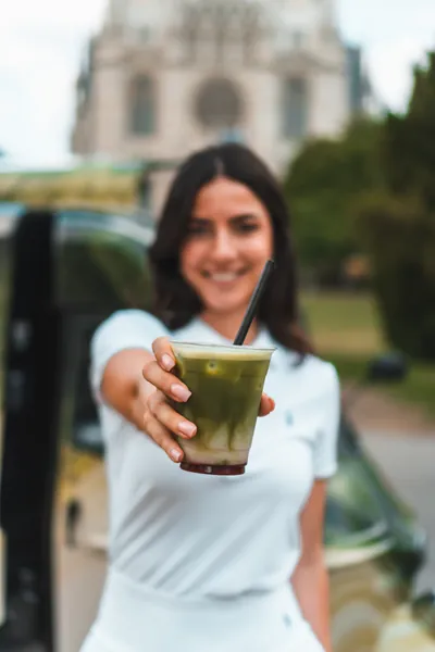 Person präsentiert einen Iced Matcha vor dem Matchamobil